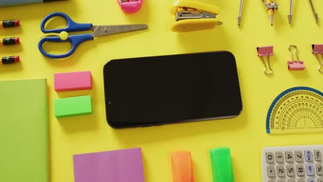 Video-of-diverse-office-tools,-tablet-and-smartphone-with-copy-space-on-yellow-background