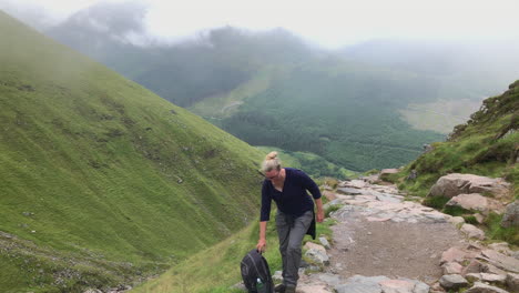 female hiker with heavy backpack rests for a while at ben nevis mountain in scotland, wide shot