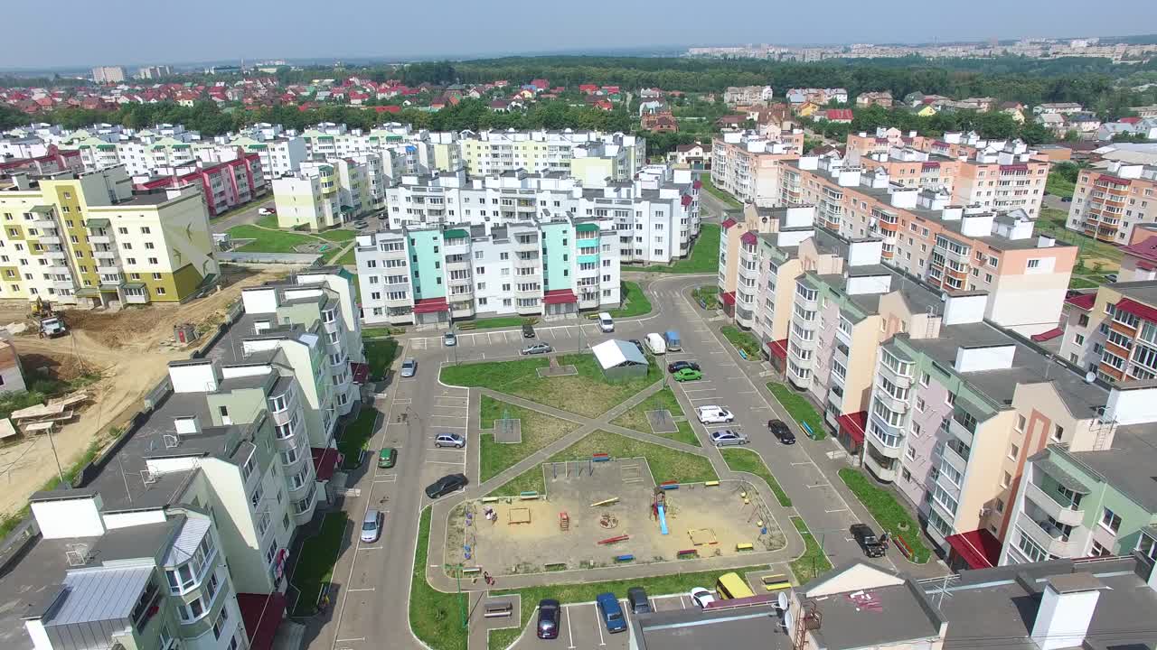 Flying over the new built high-rise buildings and many roads for cars in the residential complex in summer. New area in the city with modern buildings in a sunny day. Aerial view