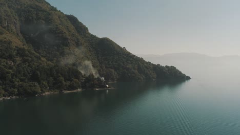 drone aerial shot of tzununa bay, smoke coming out of a house, lake atitlan, guatemala