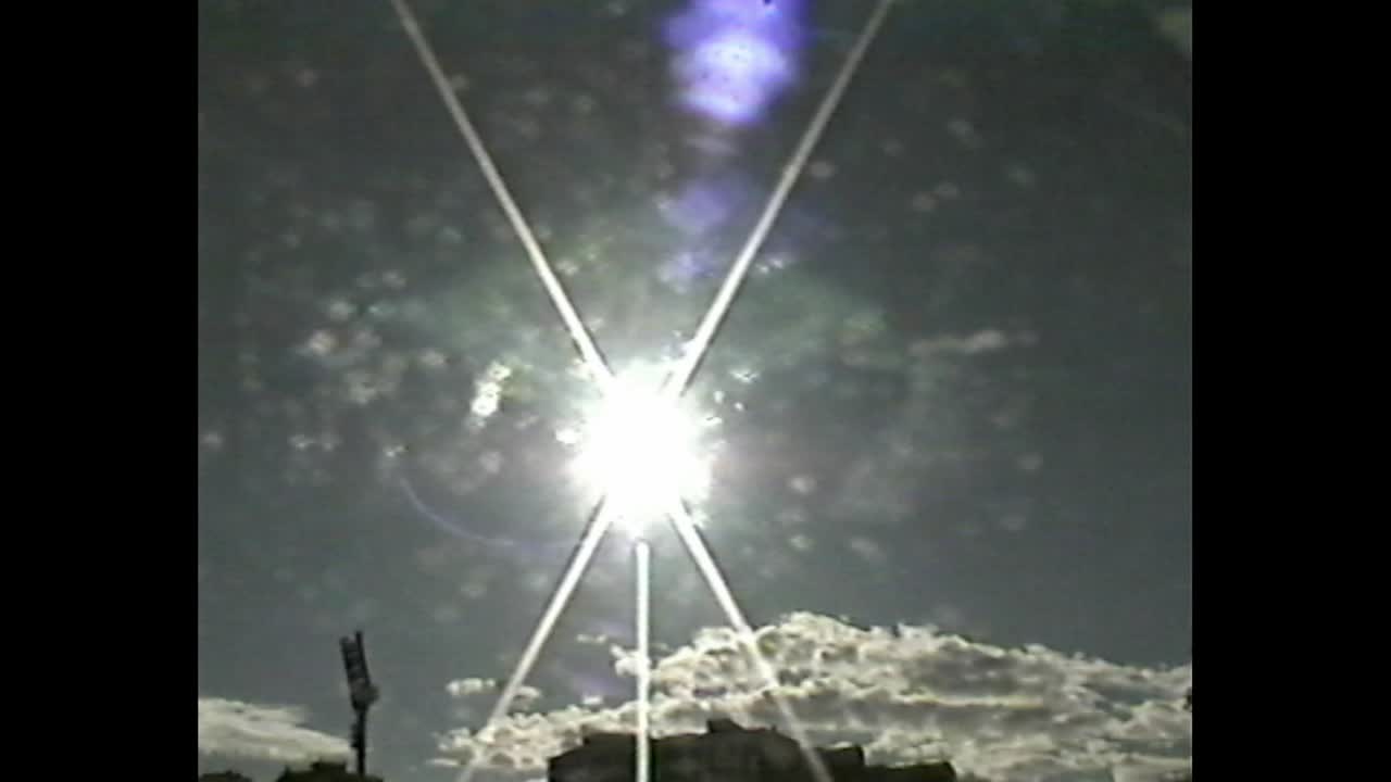 Sun flare and clouds over urban skyline at midday