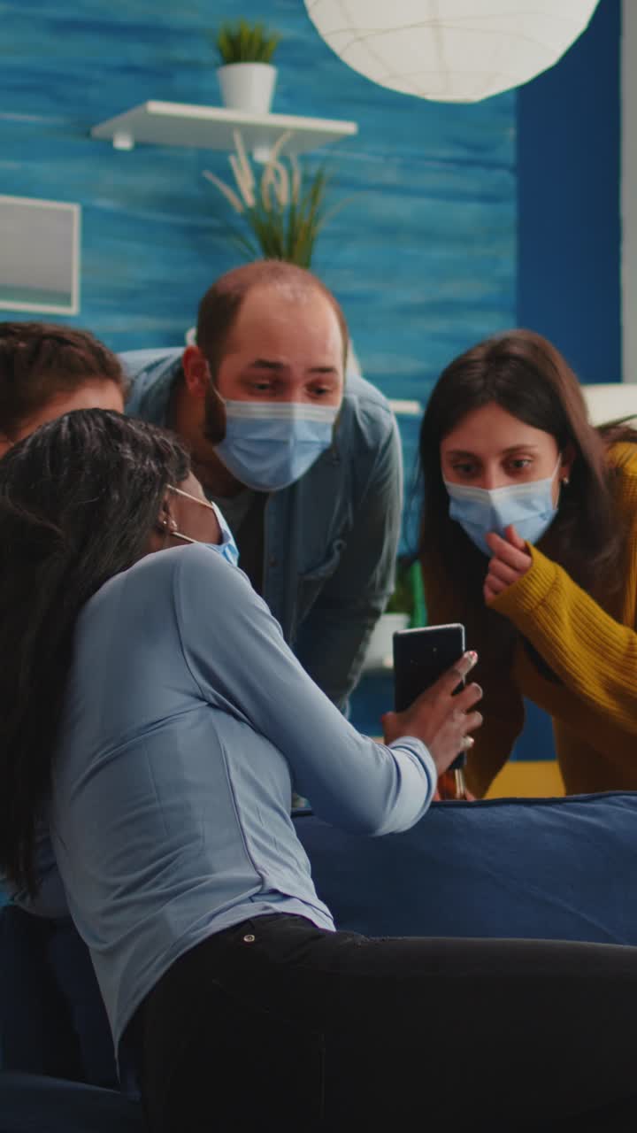 Vertical video: African woman showing funny clip on smartphone hanging out at home