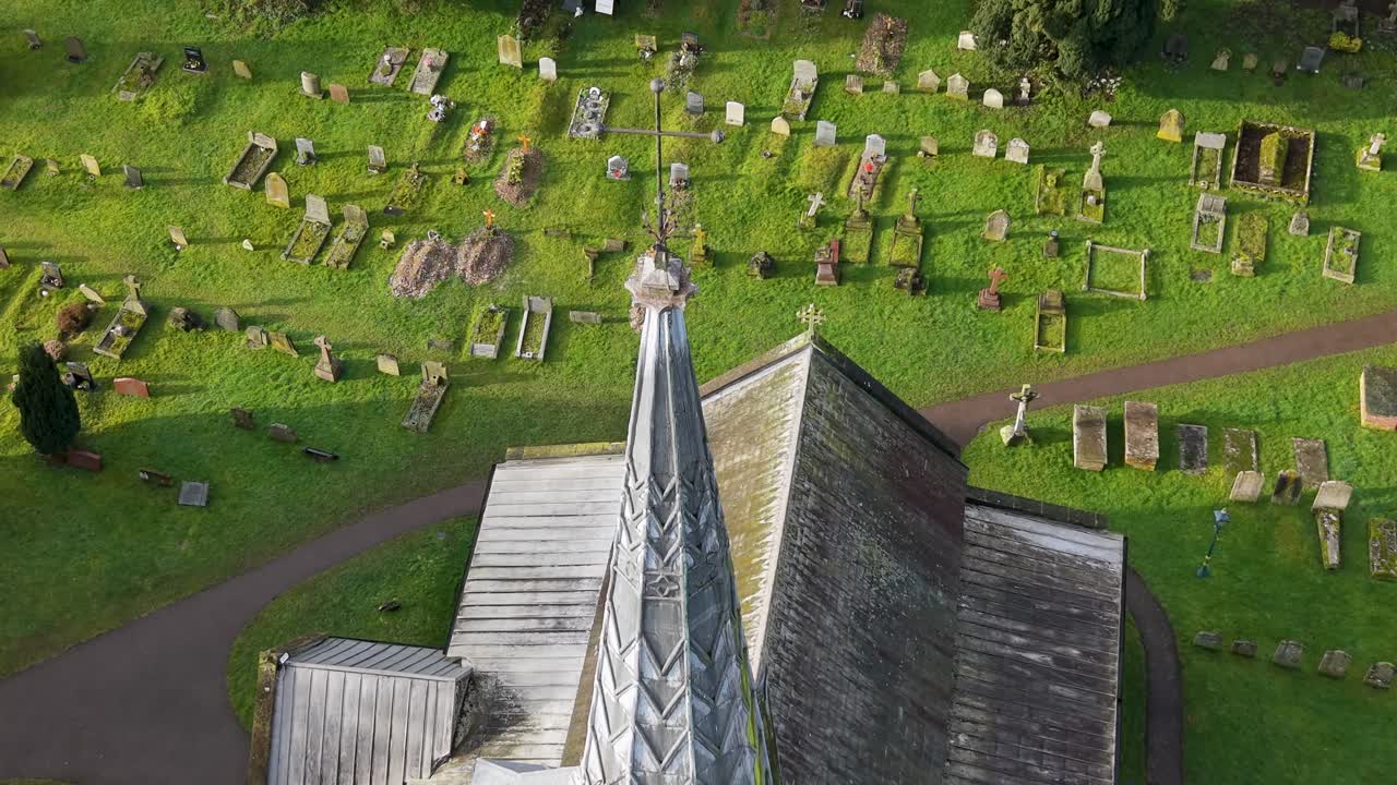 Drone push toward church spire tilts down from cemetery to roof