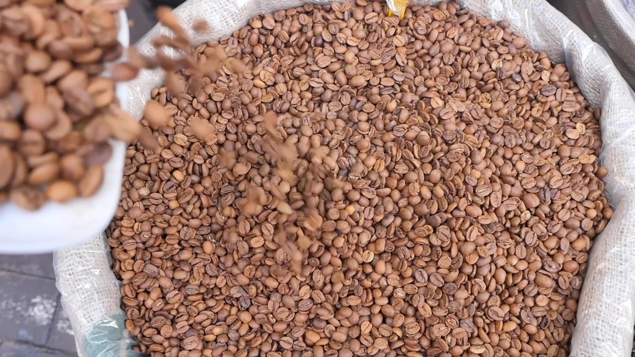 Chicchi di caffè tostati che si riversano in un grande sacco.