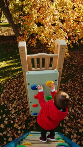toddler climbing playground wall in autumn