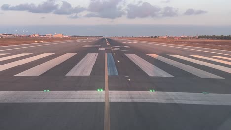 take off run of a medium size jet taking off from runway 24 just before sunset, with the shadow of the plane on the right side