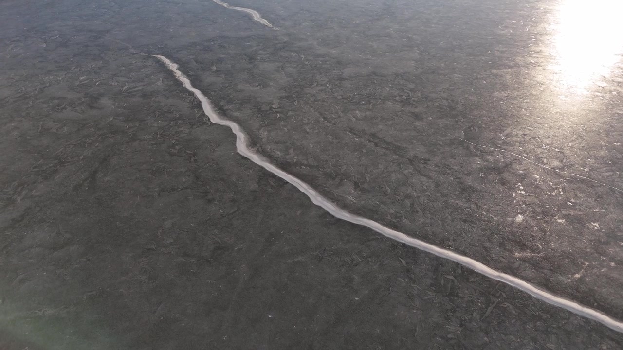A frozen lake from a drone. Snow patches. Ice cracks.