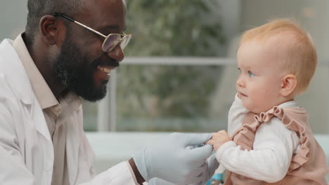 african american pediatrician playing with baby during health checkup