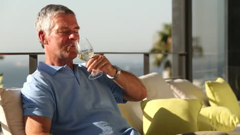 man drinking a glass of wine while sunbathing