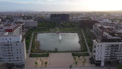 Aerial-back-traveling-over-Montpellier-Port-Marianne-city-pond-and-park-sunset