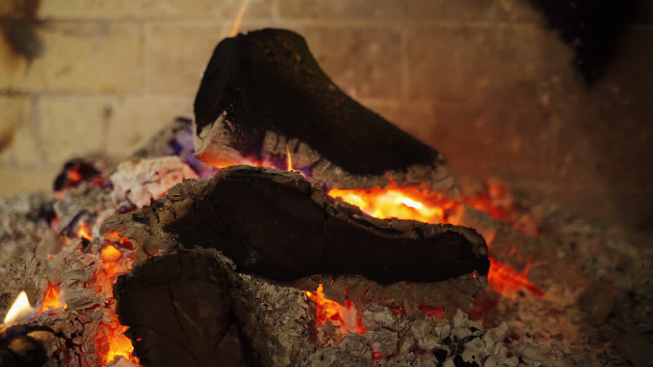 Smoldered logs in white ashes. Background of glowing wood. Black logs burning out in fireplace. Comfortable heat place at home.