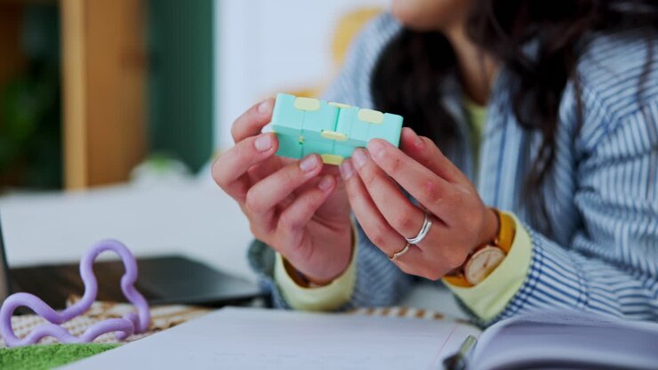 Woman playing with infinity cube at desk