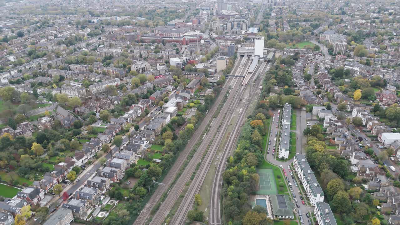 Drone footage following railway line through Ealing Broadway station showcasing transit infrastructure in London, UK