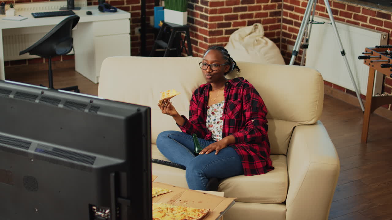 Glad kvinde spiser et stykke pizza og ser film