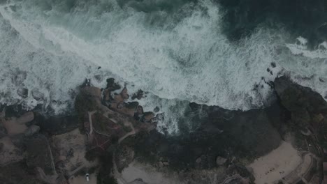 waves crash white foaming onto the rocks of the indonesian coast near baron beach