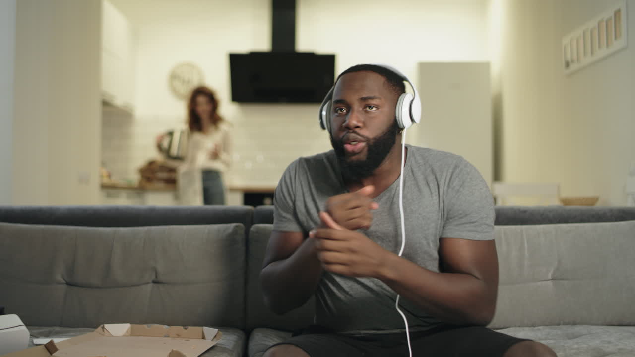 Smiling african american man dancing in headphones at modern kitchen