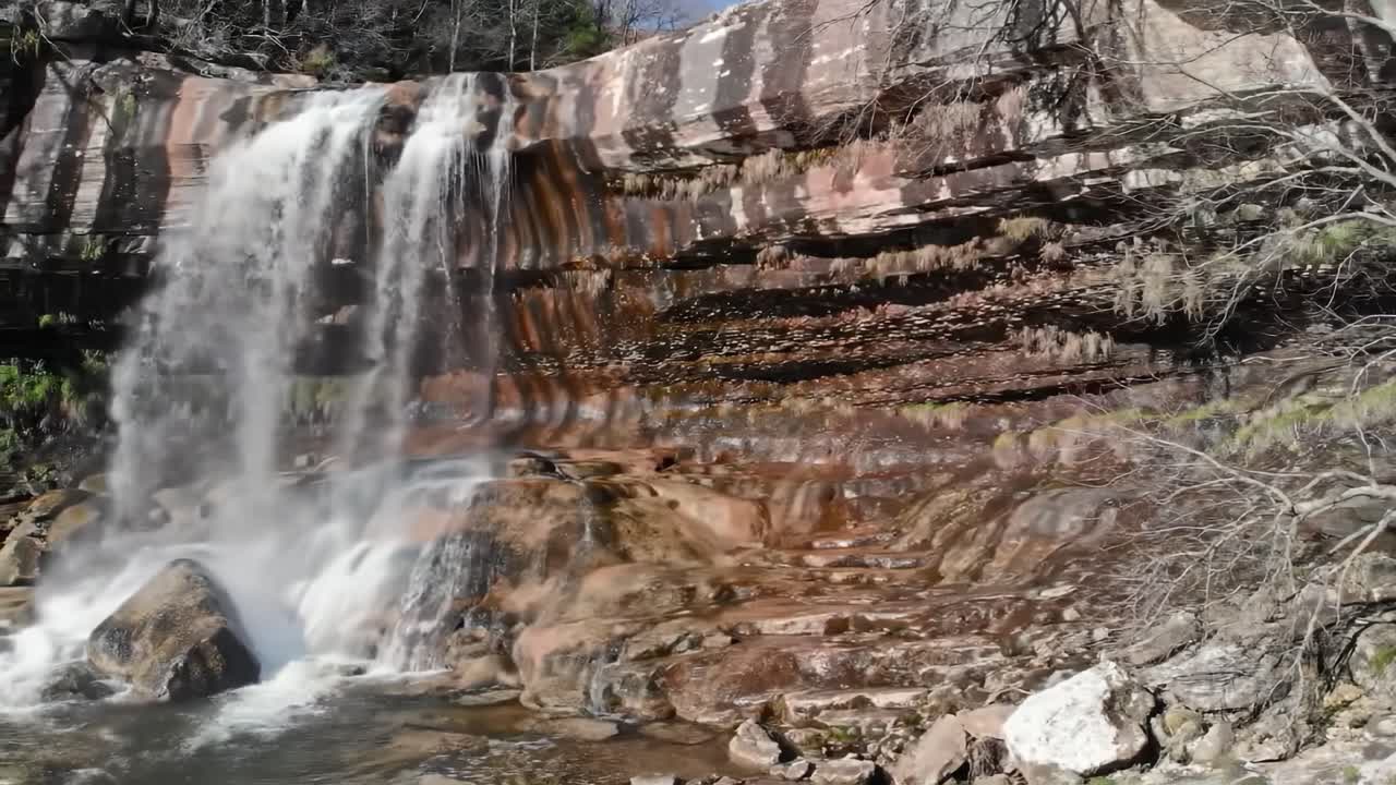 Majestic Waterfall Cascading Over Layers of Rock, Surrounded by Vibrant Greenery and Clear Blue Skies, Capturing the Beauty of Nature's Wonders