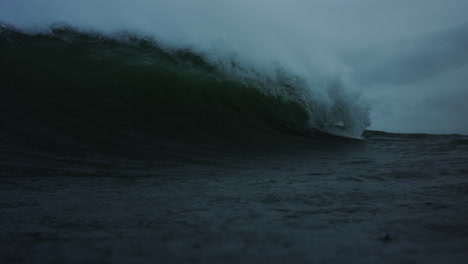 lip of wave crashes forward on sloping water in ocean, view down barrel