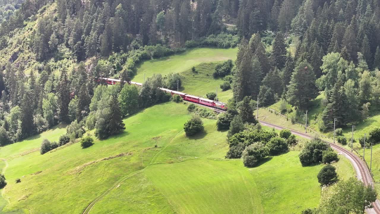 Red Train Winding Through Lush Green Hills and Forests