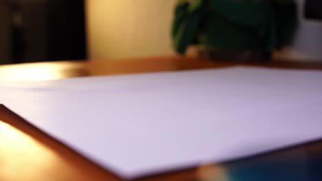 gray pencil is placed on a paper on a wooden desk and then picked up by a hand