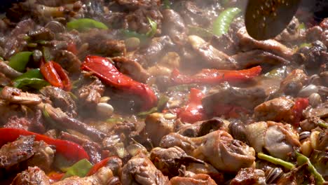 chef moving the meat of the paella with the shovel in a detailed plane, first forward and then to the side