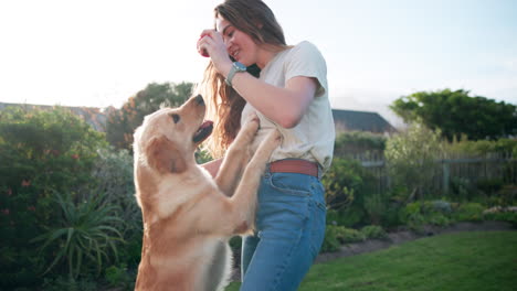 woman playing with her golden retriever in the garden