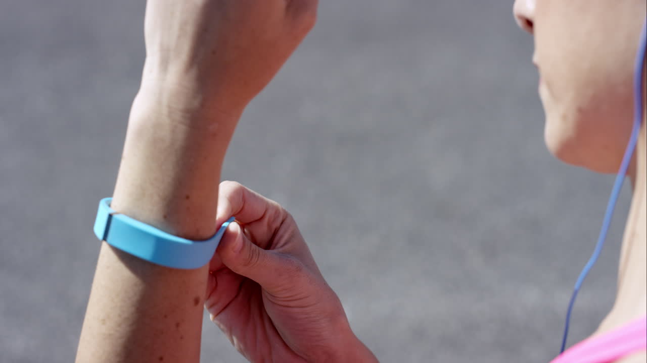 Athletic woman putting on fitness tracker before her run
