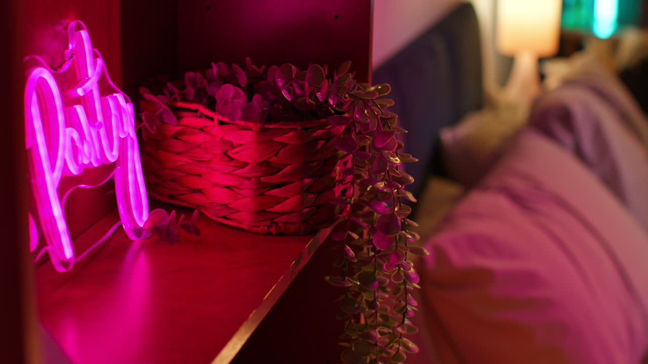 letrero de "fiesta" de neón rosa en el estante con la planta