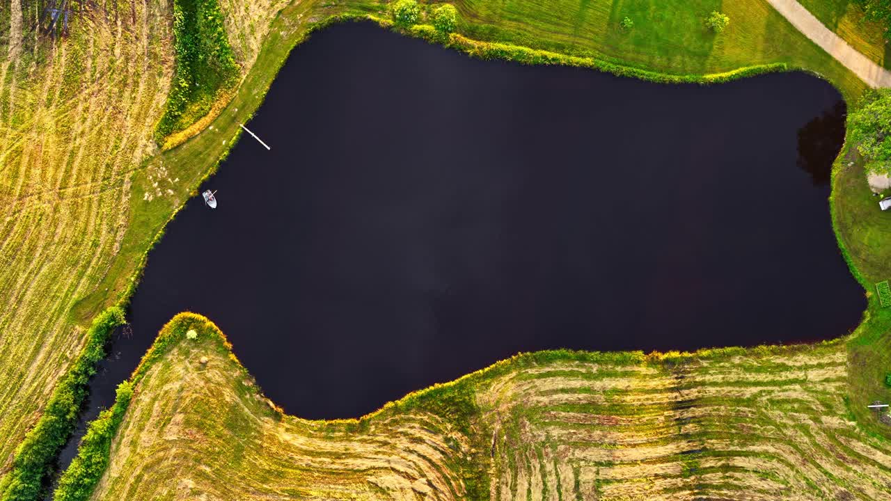 A boat moves across a small lake in timelapse, seen from directly above