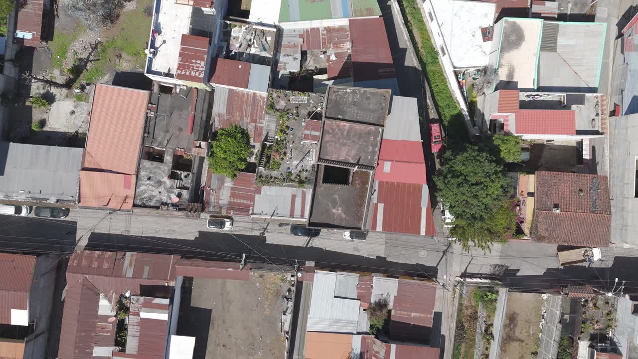 fotografía aérea de un barrio urbano densamente poblado en guatemala, que muestra techos de metal ondulado, calles y vegetación