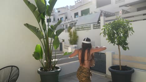 mujer bailando en un patio con plantas tropicales