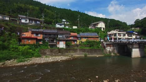 mesmerizing aerial view moves backward over a serene river, away from charming village houses along its peaceful shores