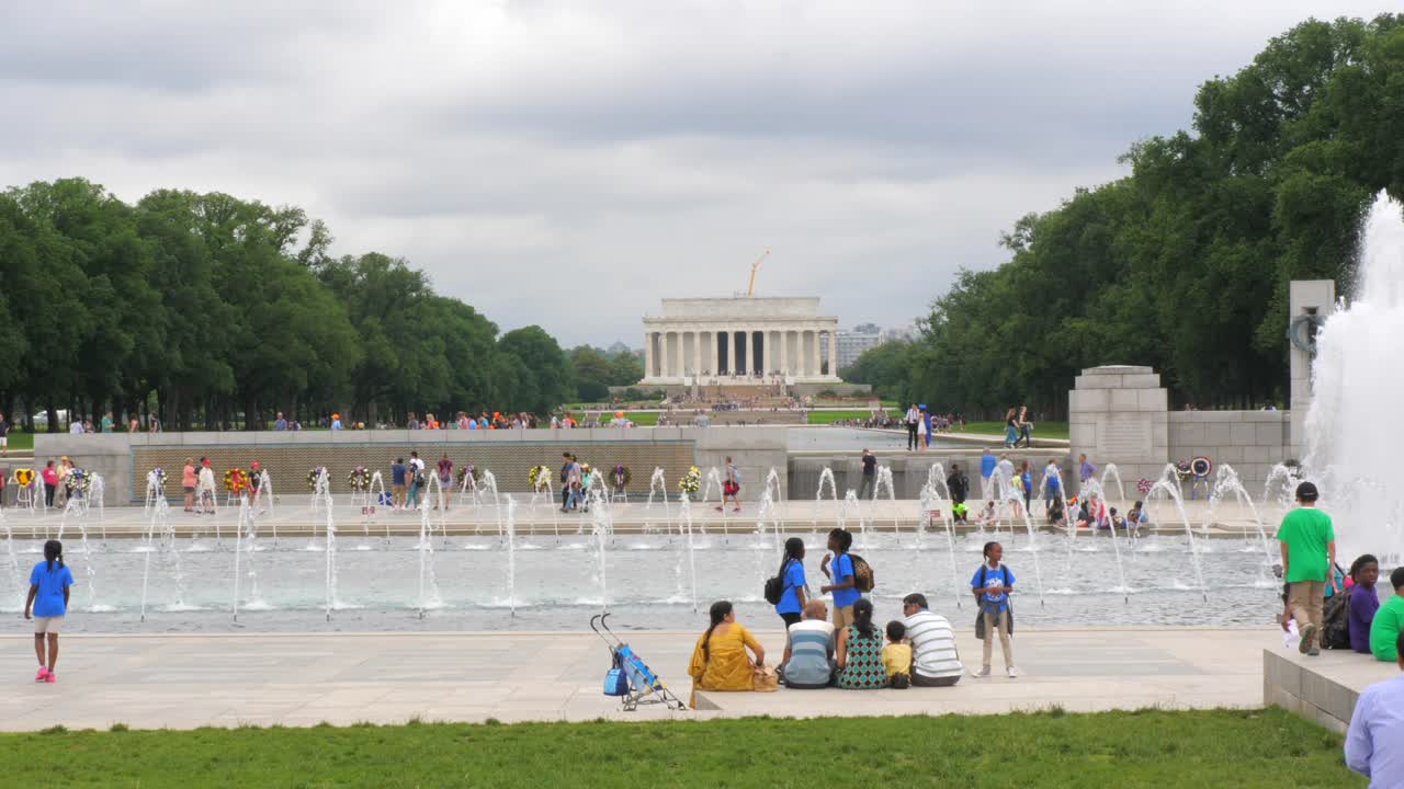 Lincoln memorial temple with tourists wearing colorful shirts and water fountain, Washington, D.C., static slow motion