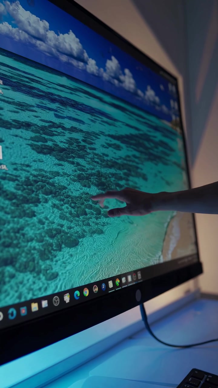 Persona con monitor touchscreen in un ufficio poco illuminato