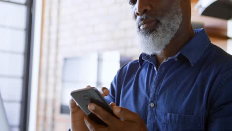 senior man using mobile phone in kitchen 4k
