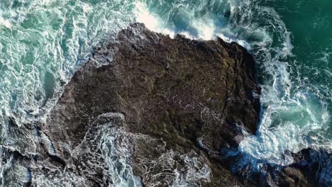 overhead view of foaming sea waves hitting rocky shore