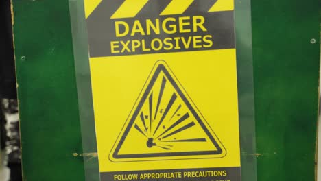 danger explosives sign board with people wearing military outfit in background