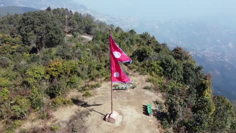 Una-Vista-Aérea-De-Una-Bandera-Nepalí-Que-Sopla-En-El-Viento-En-La-Cima-De-Una-Colina-En-Nepal