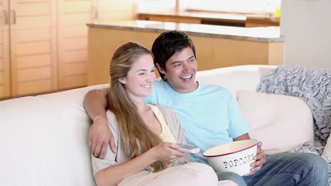 a couple watching tv with popcorn