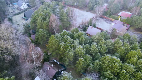 aerial drone orbit around suburban house in woods among tall green trees and rural fields