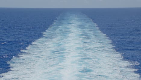 Slow-motion-shot-of-vast-caribbean-ocean-and-trails-from-cruiseliner
