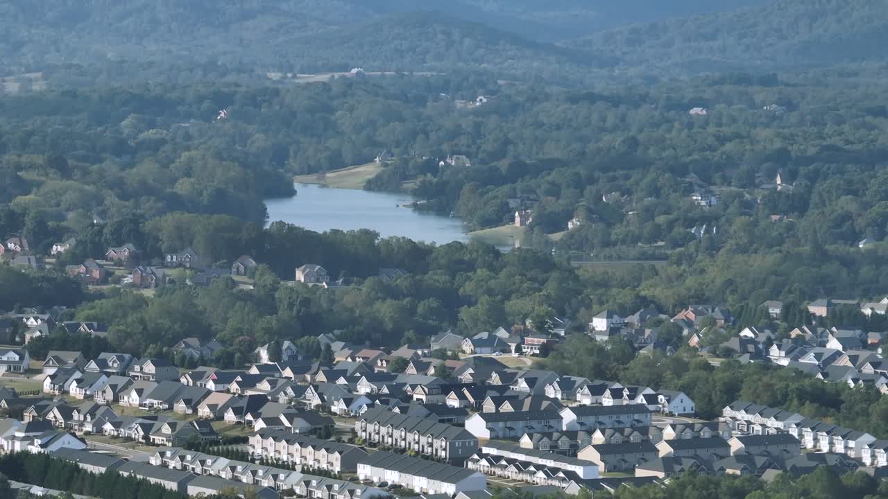 Residential area with row of modern houses and homes in idyllic suburb of town. Aerial wide shot. Idyllic forest landscape of America with lake in distance