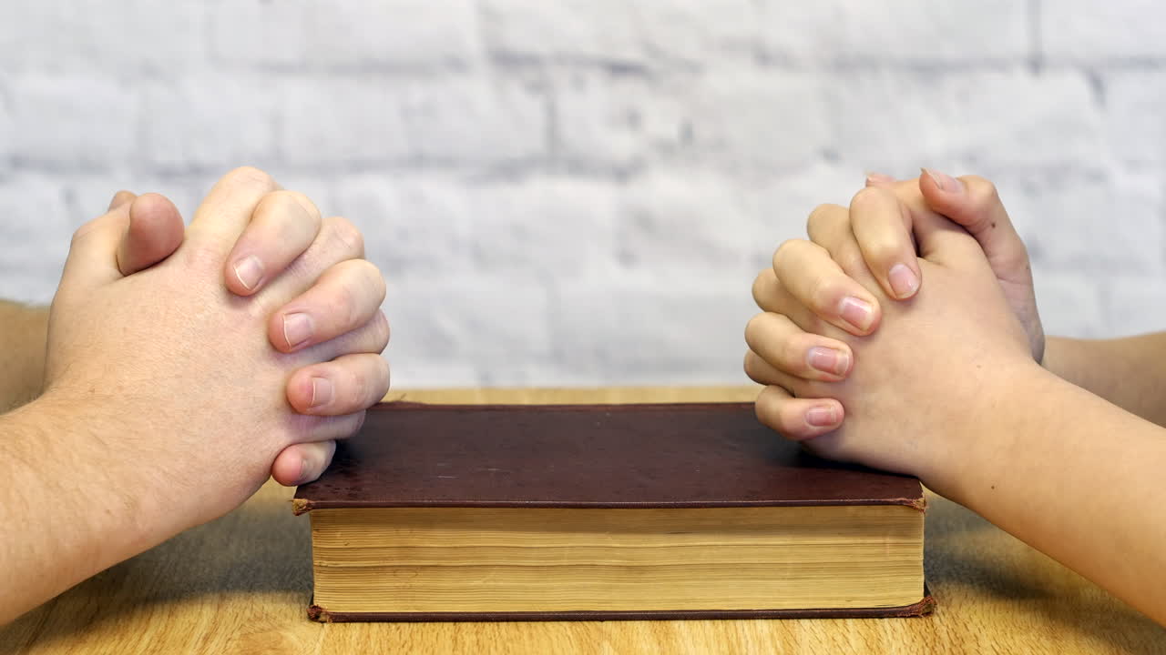 탁자 위에 성경을 놓고 여성과 기도하는 남자의 클로즈업