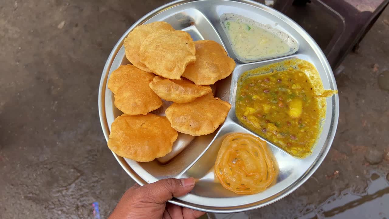 Close up shot of puri bhaji served with potato curry along jalebi, raita at a Bihari shop in Dhanbad at daytime.