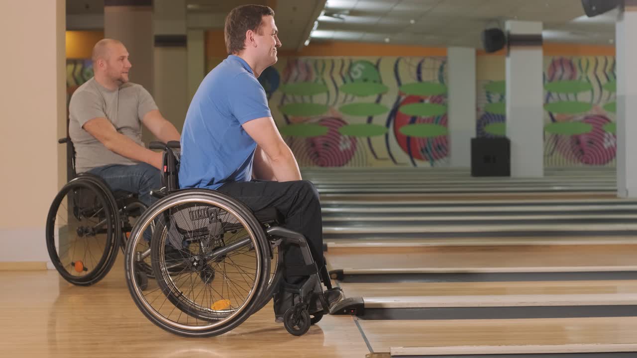 dos jóvenes discapacitados en sillas de ruedas jugando al bolos en el club