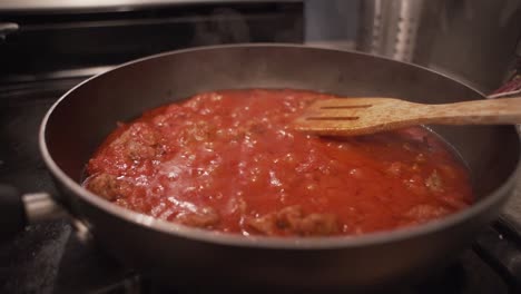 salsa de espagueti roja hirviendo en una sartén de teflón en una estufa