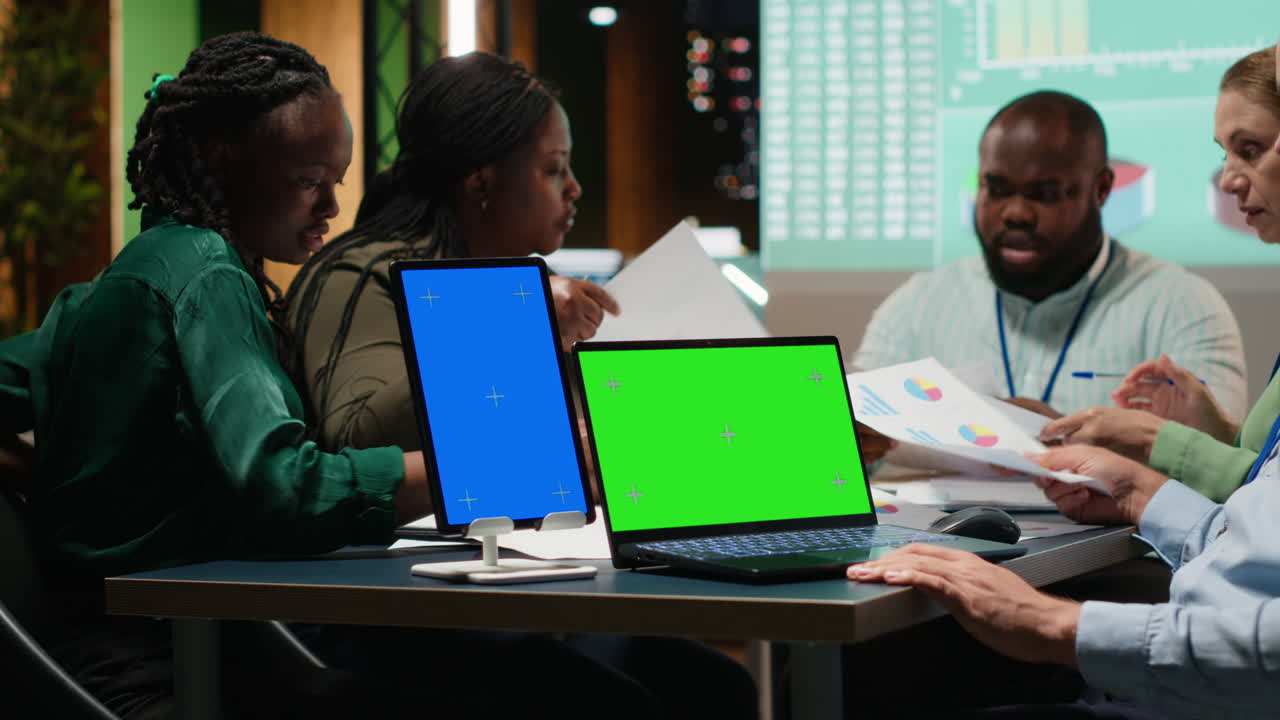 Multiethnic team of experts in a meeting with a chroma key laptop