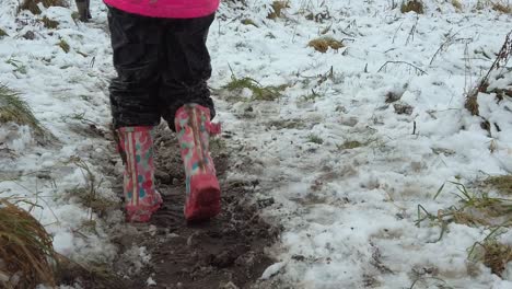 slow motion child walking in wellies in snow field