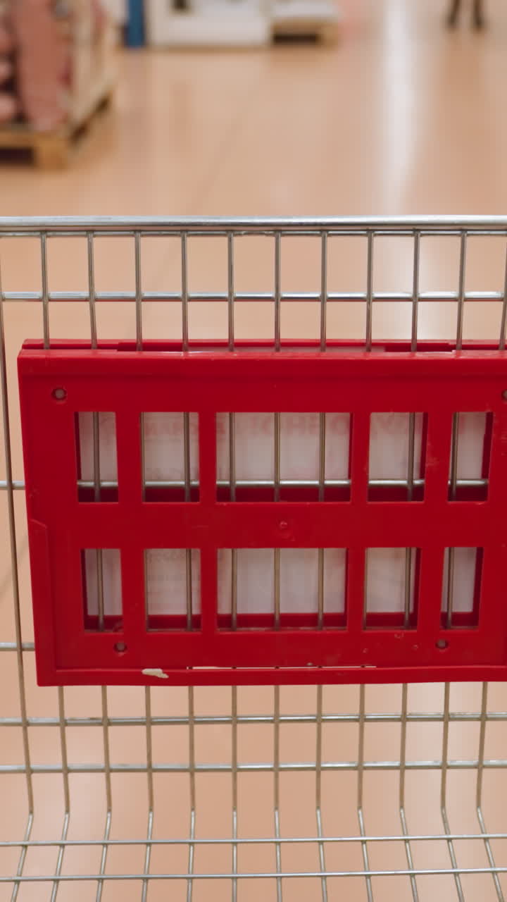 쇼핑 트롤리를 쇼핑몰의 복도 아래로 옮기는 사람. 휴대용 카메라로 촬영된 이 영상은 쇼핑 경험을 보여 주며, 역동적인 움직임과 활기찬 소매 환경을 강조합니다.