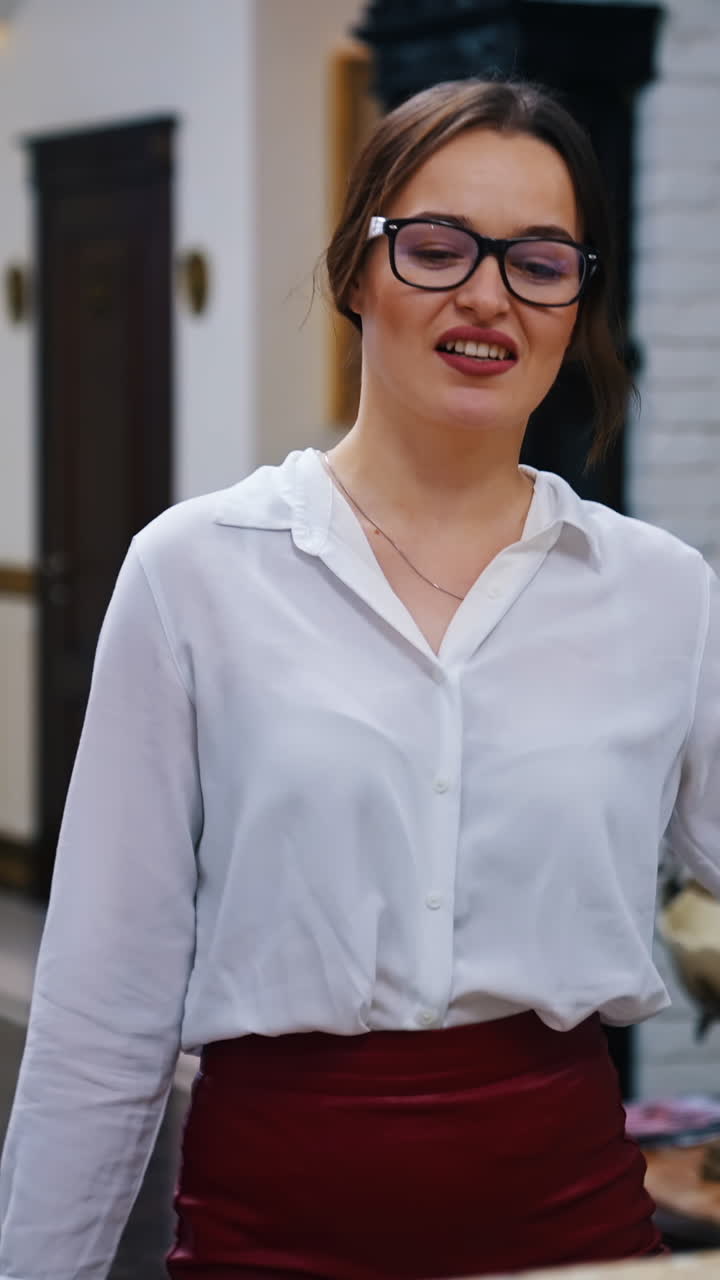 Charming lady with suitcase in the reception lobby. Girl approaching hotel reception to take the key. Portrait of gorgeous woman pressing bell button at reception desk. Vertical video
